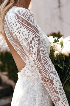 the back of a woman's white wedding dress with long sleeves and lace detailing