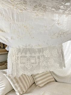 a canopy bed with white linens and pillows