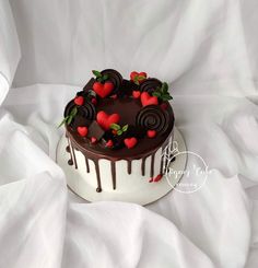 a chocolate cake with strawberries and chocolate icing on top is sitting on a white sheet