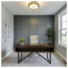 a desk in the corner of a room with two paintings on the wall behind it