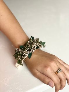 a person's hand with a ring on it and flowers attached to the wrist