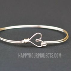 a silver bracelet with a knot in the middle and a heart on it's end