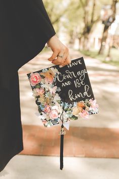 a person holding a sign with flowers on it