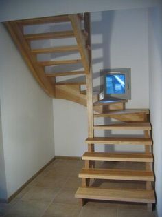 a computer monitor sitting on top of a wooden stair case next to a tiled floor