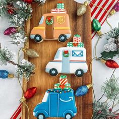 decorated cookies sitting on top of a wooden cutting board next to christmas trees and decorations