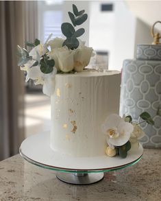 there is a white cake with flowers on the top and bottom, sitting on a plate