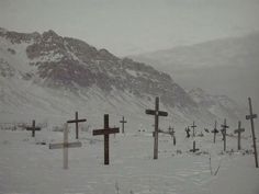 several crosses in the snow with mountains in the background