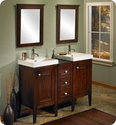 two bathroom sinks with mirrors above them in a room that has green walls and wood flooring