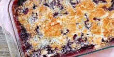 a casserole dish with blueberries and crumbs in it on a pink napkin