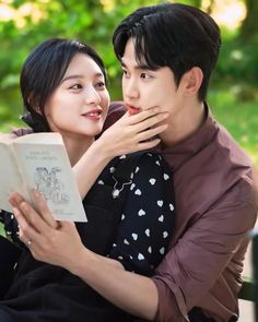 the young couple is hugging each other while holding an open book