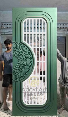 two men standing in front of a green door with intricate carvings on the outside and inside