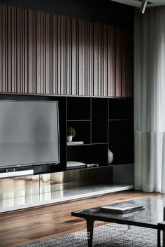 a living room with a large flat screen tv on the wall next to a coffee table