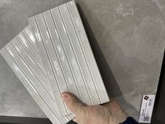 a hand holding some white tiles on top of a table