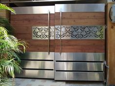 two metal doors with decorative designs on the side of a building next to a potted plant