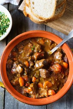 a bowl filled with stew next to bread on top of a wooden table and the words italian veal stew above it