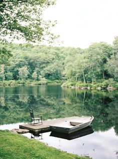 a boat sitting on top of a body of water next to a wooden dock with a chair