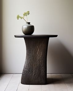 a vase sitting on top of a wooden table next to a flower in a vase