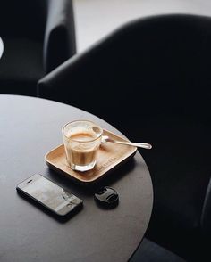 a table with a cell phone on it and a cup of coffee next to it