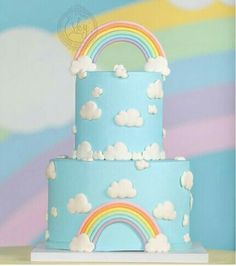 there is a blue cake with rainbows and clouds on it