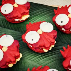 red and white decorated cookies sitting on top of a green leaf next to stuffed animals