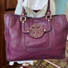 Tory Burch Pretty Purple Shoulder Bag Satchel Handbag Purse Genuine Pebbled Leather In Purple Gold Tone Hardware Large Round Gold Tone Rimmed Purple Leather Tory Logo Front And Center Has Slip Pocket Under Logo Back Exterior Studded Slip Pocket 2 Rolled Satchel Handles Square Gold Handle Mounts Sides Have Top Snaps To Tighten Ends Or Open For More Room Bottom Has 4 Gold Tone Rivets For Feet Magnetic Snap Top Closure Interior Lined In Light Tan Fabric/ Tory Round Logos Inside Contains 1 Large Zip Luxury Purple Satchel With Handles, Purple Top Handle Shoulder Bag With Leather Handles, Luxury Purple Tote Shoulder Bag, Classic Purple Bag With Detachable Handle, Luxury Purple Satchel With Gold-tone Hardware, Designer Purple Shoulder Bag With Removable Pouch, Luxury Purple Shoulder Bag With Removable Pouch, Luxury Purple Shoulder Bag With Double Handle, Purple Top Handle Bag With Leather Handles