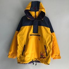 a yellow and blue jacket hanging up on a wall with the hood pulled back over it's shoulder