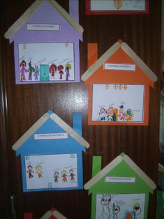 four houses with pictures on them hanging from the wall in front of a door that is decorated with children's artwork