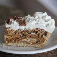 a piece of cake with white frosting and nuts on top sitting on a plate