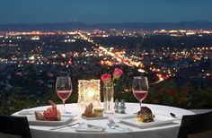 a table topped with two glasses of wine and plates filled with food on top of it