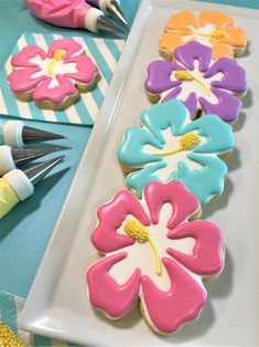 decorated cookies on a plate with paintbrushes next to them