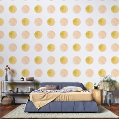 a bed sitting in front of a wall with yellow circles on it's side