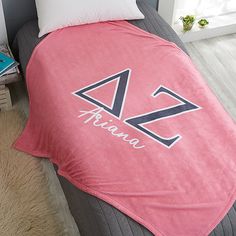 a bed covered in a pink blanket with the name arian on it and two pillows