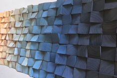 a wall made up of different shades of blue and white paper with wood strips on it