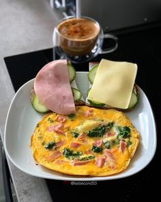 an omelet with ham, cheese and cucumbers on a white plate