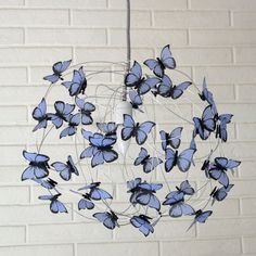 a mobile made out of blue butterflies hanging from a string on a brick wall background