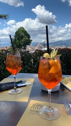 two glasses filled with drinks sitting on top of a table