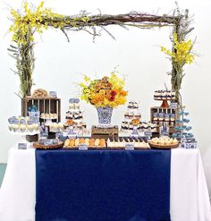 a table topped with lots of cupcakes and cakes next to a vase filled with flowers