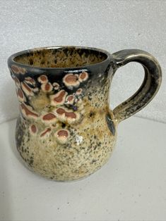 a brown and black cup sitting on top of a white counter next to a wall