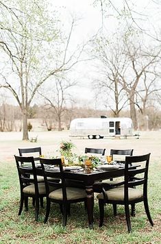 a table and chairs in the grass with an rv in the background