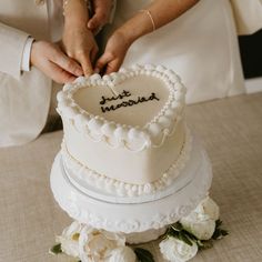 a bride and groom cutting their wedding cake with the words just married written on it