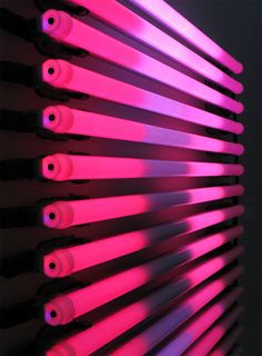 pink lights are shining on the side of a radiator in a dark room