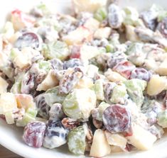 a white bowl filled with fruit salad on top of a wooden table