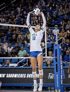 a female volleyball player jumping up to hit the ball