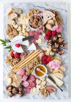 a marble platter filled with cheese, crackers, nuts and other food items