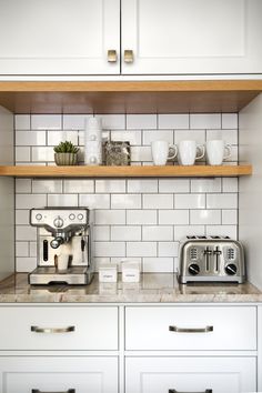 a coffee maker and toaster are sitting on the counter in this white tiled kitchen