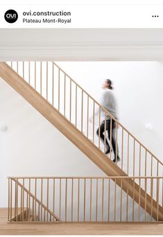 there is a man walking down the stairs in an apartment that has white walls and wood handrails