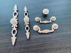 three pieces of jewelry sitting on top of a wooden table next to another piece of furniture