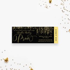 a black and gold party ticket with confetti on the table next to it