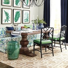 a dining room table with chairs and pictures on the wall above it, along with two green plant vases