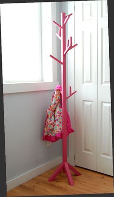 a pink coat rack stands next to a white door